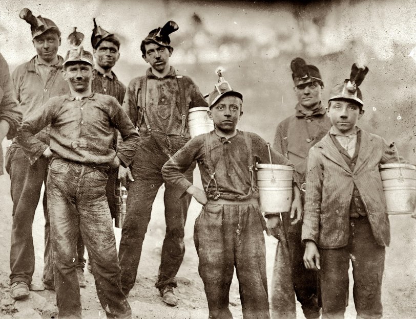 "Drivers and Trappers Going Home." Barnesville Mine, Fairmont, West Virginia. October 1908. View full size. Photograph by Lewis Wickes Hine. Note oil-wick lamps on the hats, and lunch pails. Trappers were boys who opened trapdoors to let coal cars pass and then closed them again to maintain proper airflow in the tunnel ventilation system.

One trapper's description of the job, which paid about $1.60 a day:

Trappers were responsible for opening and closing the underground  ventilation doors.  In those old mines, they had a system of doors between sections to direct the flow of air. Air was supposed to go up the main haulage and back to the fan.  So a trapper sat all day by his door with an oil lamp on his cap.  There was a "manhole" - a shelter hole in the wall by the track. The motorman would blink his light at me, and I'd throw the switch and open the door for him. Then, I'd jump into the manway until he was past, and run out and close the door. A trip would come along about every hour. Was I bored or lonely? Well, it was my job.