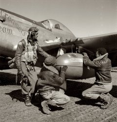 March 1945. Ramitelli, Italy. 332nd Army Air Forces Fighter Group. "Tuskegee airman Edward C. Gleed of Lawrence, Kansas, Class 42-K, with two crewmen adjusting an external 75 gallon drop tank on the wing of the P-51D Creamer's Dream." Medium format negative by Toni Frissell. View full size.