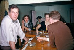Along with the "tterrace lost and found" slides my friend and I came across in the spare room of his house a month back was a mini-trove of Kodachromes of his folks in 1953 he didn't know about. But he did instantly recognize the recreation room and bar his dad had built in the basement of their San Francisco home. A big holiday shindig is underway with friends and relations; other slides hint that it might be Thanksgiving. Meanwhile: set 'em up. His folks always knew how to really throw a party. Later in the decade and into the early 60s they took on a distinct Tiki flavor, not unusual for the time in general, but especially so for Pacific-theater WWII vets like his dad. That's his mom in the background attending to the record player. Hey buddy, you got a light? View full size.