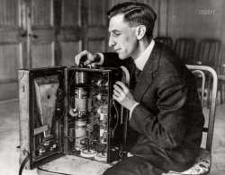 April 1922. Chicago. "The Singing Valise -- F.W. Dunmore, of the U.S. Bureau of Standards radio laboratory, with radio built in suitcase." Underwood & Underwood photo. View full size.

CARRIES RECEIVING SET
ABOUT IN SUIT CASE

Government Expert Astounds Gathering of Engineers With Demonstration of Singing Valise -- Explains Small Instrument Capable of Controlling Mechanism at Great Distances

&nbsp; &nbsp; &nbsp; &nbsp; CHICAGO, May 19 -- "The Singing Valise," or "Talks-as-it-walks," may be the latest thing in radiotelephone reception, displayed to the amazement of delegates attending the American Institute of Engineers meeting here last month at the Drake Hotel, by F.W. Dunmore of the radio laboratory of the U.S. Bureau of Standards. Incidentally, it may be pointed out that the engineers at their spring meeting are paying a great deal of attention to radio ...

&nbsp; &nbsp; &nbsp; &nbsp; Mr. Dunmore has a small suit case about one-third the size of an average grip. In the body of the suit case he has batteries, condensers and other paraphernalia of a radiophone receiver. Neatly packed in the cover part is a loud speaker and a loop aerial of tiny wire. The only opening in the sides of the valise is for the mouth of the loud speaker.

What It Does.

&nbsp; &nbsp; &nbsp; &nbsp; While the engineers were gathered in the French Room of the Drake, all windows closed, Mr. Dunmore opened the grip, turned the aerial director toward the Westinghouse broadcasting station KYW, and at once the voice of the announcer of a radio news service was heard.

&nbsp; &nbsp; &nbsp; &nbsp; "That's easy," said Mr. Dunmore, and, closing the satchel, he took hold of the handle and walked about the room. The news bulletins continued to come and were heard in all parts of the room. He walked to every corner of the room and the voice continued until KYW, having completed the news bulletins, signed off.

&nbsp; &nbsp; &nbsp; &nbsp; The reception of radio in a set inclosed in a leather case and all within the confines of the steel, concrete and brick structure of the hotel, amazed even those of the engineers who thought they had seen the very latest in radio reception.

&nbsp; &nbsp; &nbsp; &nbsp; Of greater practical importance, however, was the relay recorder for remote radio control, which Mr. Dunmore displayed and which he described at length in a written report to the engineers.

&nbsp; &nbsp; &nbsp; &nbsp; This instrument, not more than 15 inches square by eight inches deep, contained the mechanism by which ordinary radio telegraph code signals can be strengthened so as to make them operate and control mechanisms at great distances.

&nbsp; &nbsp; &nbsp; &nbsp; By this instrument, also from the radio laboratories of the United States bureau of standards, airships, automobiles, or units of power, electric light, and water plants can be controlled.

&nbsp; &nbsp; &nbsp; &nbsp; A machine equipped with the proper apparatus can be operated by radio through this instrument, said Mr. Dunmore. "We have perfected the instrument to furnish the control. The matter of equipping machinery to respond to this control will be simple."
